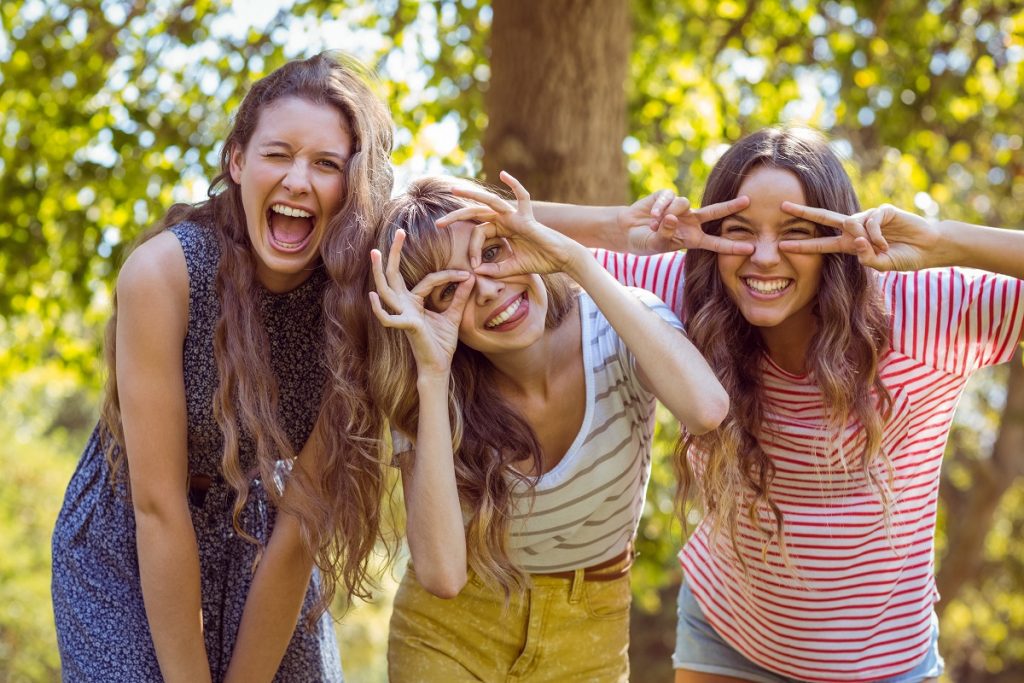 three young women smiling and being playful
