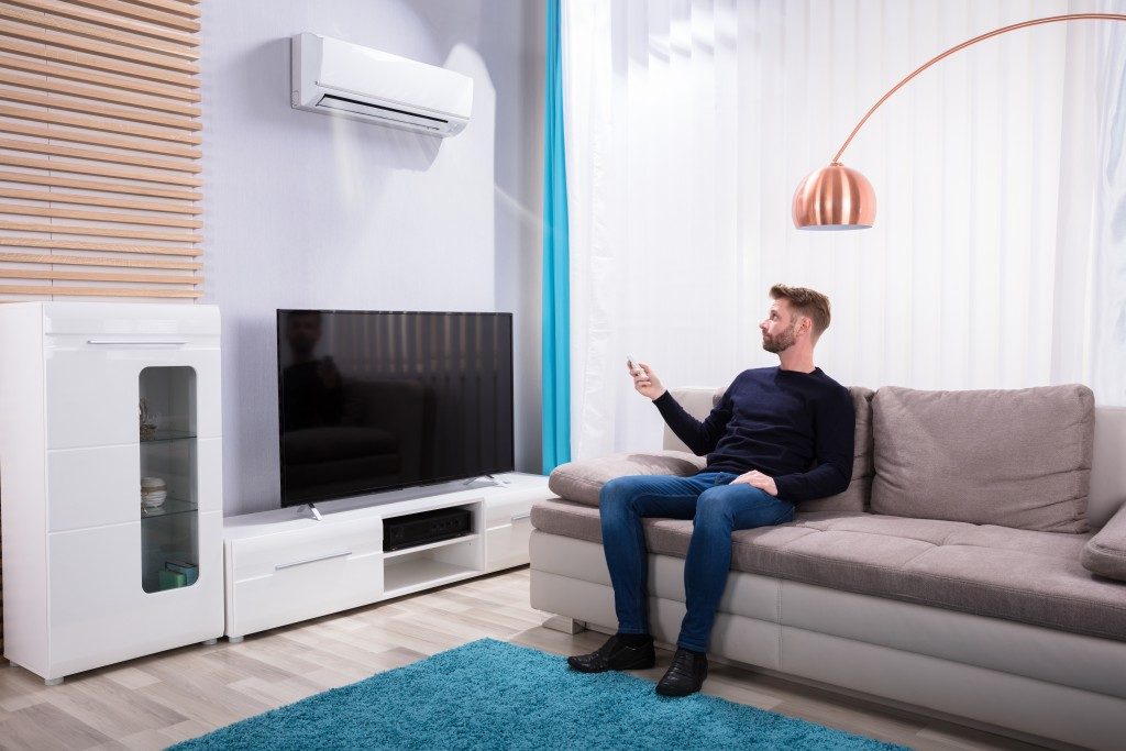 man turning on his air condition unit with remote