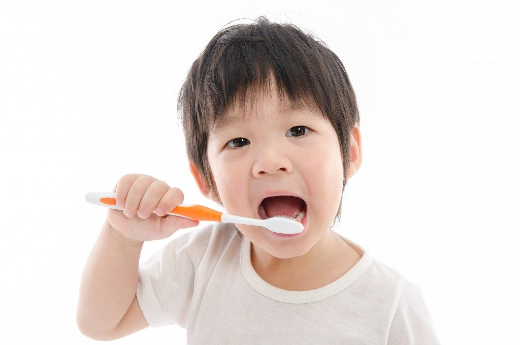 Cute asian boy brushing teeth on white background isolated