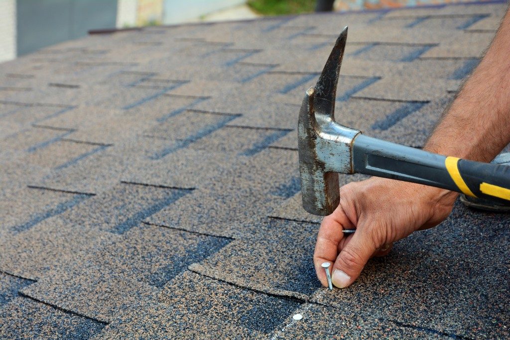 using hammer and nail on roof shingles