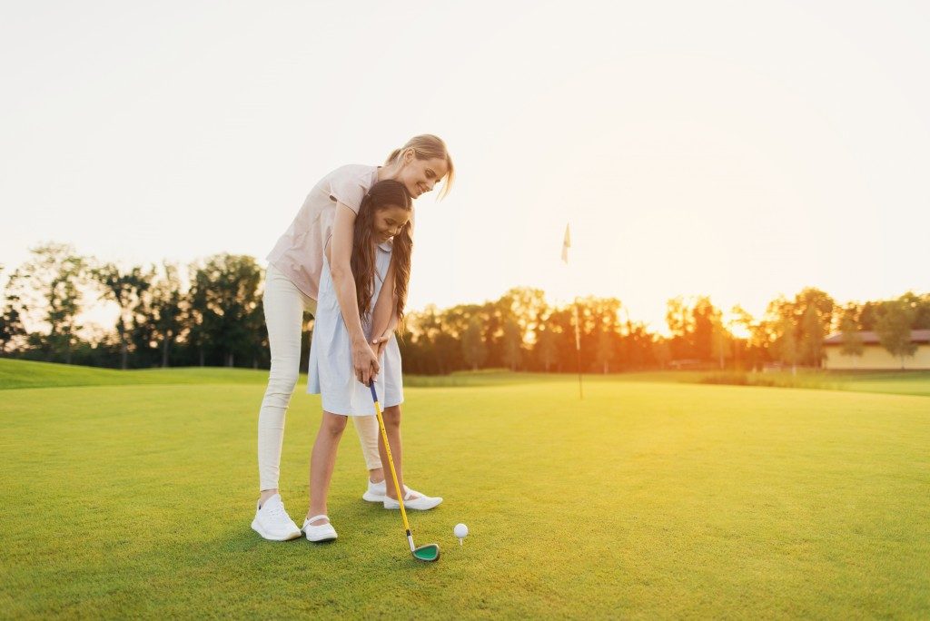 girl playing golf with her mom