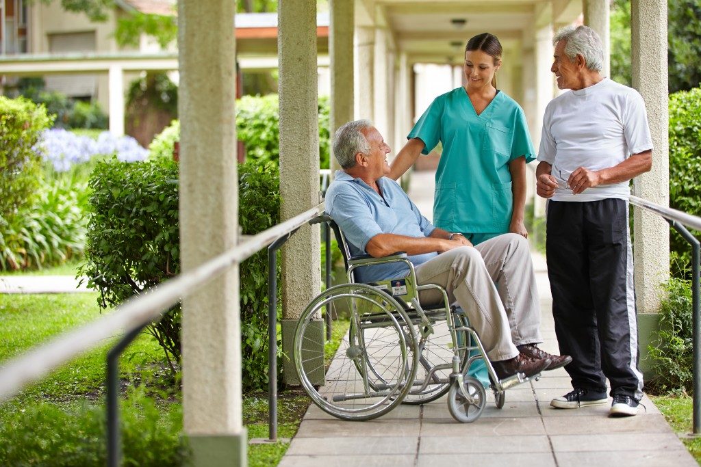 senior citizens talking to a nurse in a hospital garden