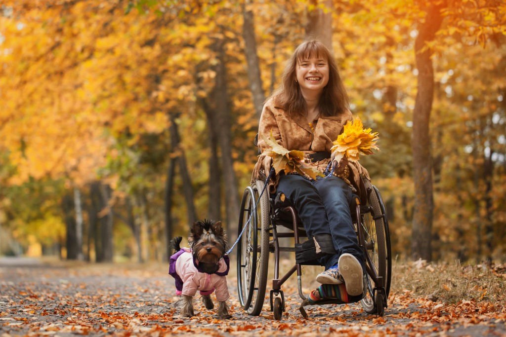 smiling happy young girl on a wheelchair with her dog