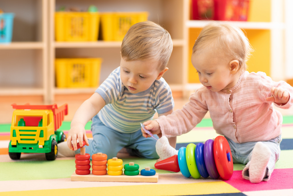 a little boy and girl holding build toys while at a playroom