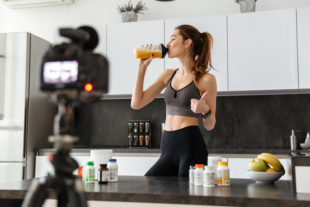 An influencer shoots a vlog about healthy food and supplements in her kitchen